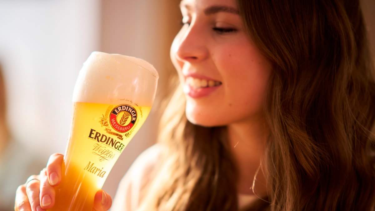 Ein Frau genießt einen Schluck aus ihrem personalisierten ERDINGER Andenken-Glas bei der Brauereibesichtigung.