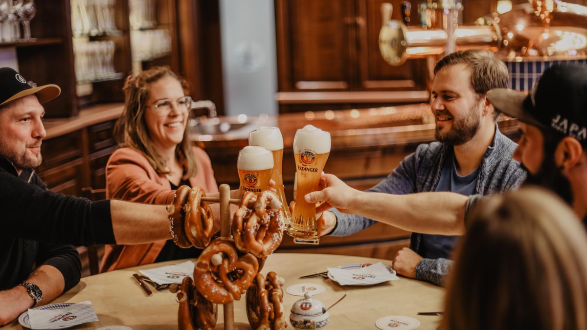 Mehrere Freunde stoßen bei ERDINGER Brauereibesichtigung mit Weißbier an.