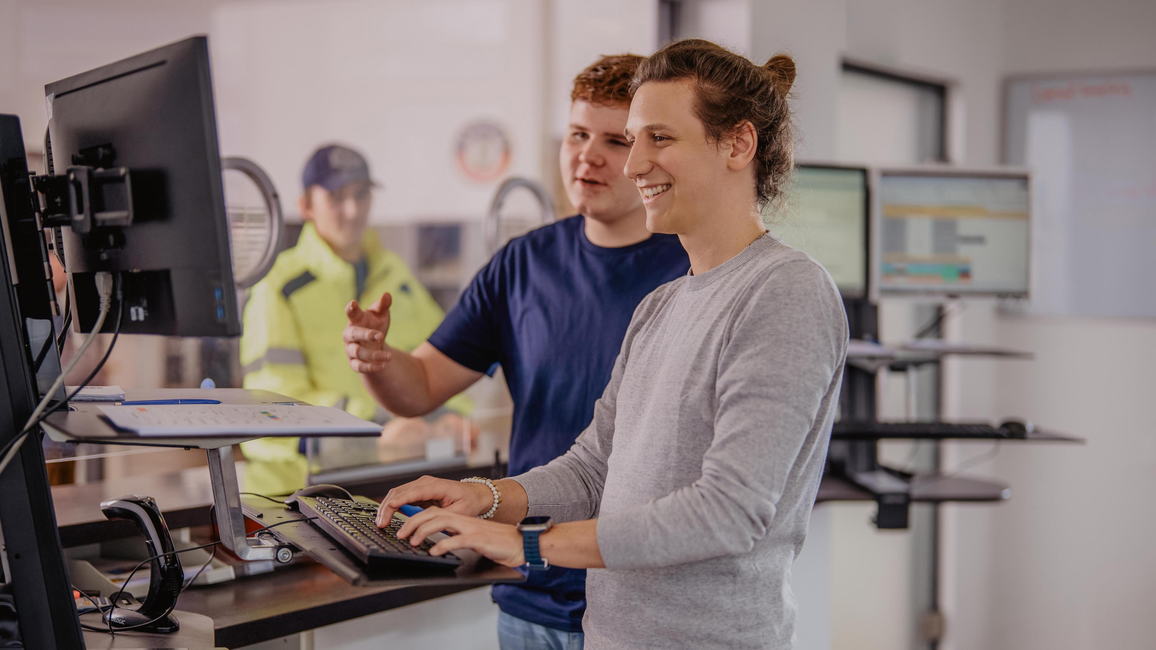 Zwei ERDINGER Mitarbeiter arbeiten zusammen vor einem Computer-Monitor in der Brauerei.
