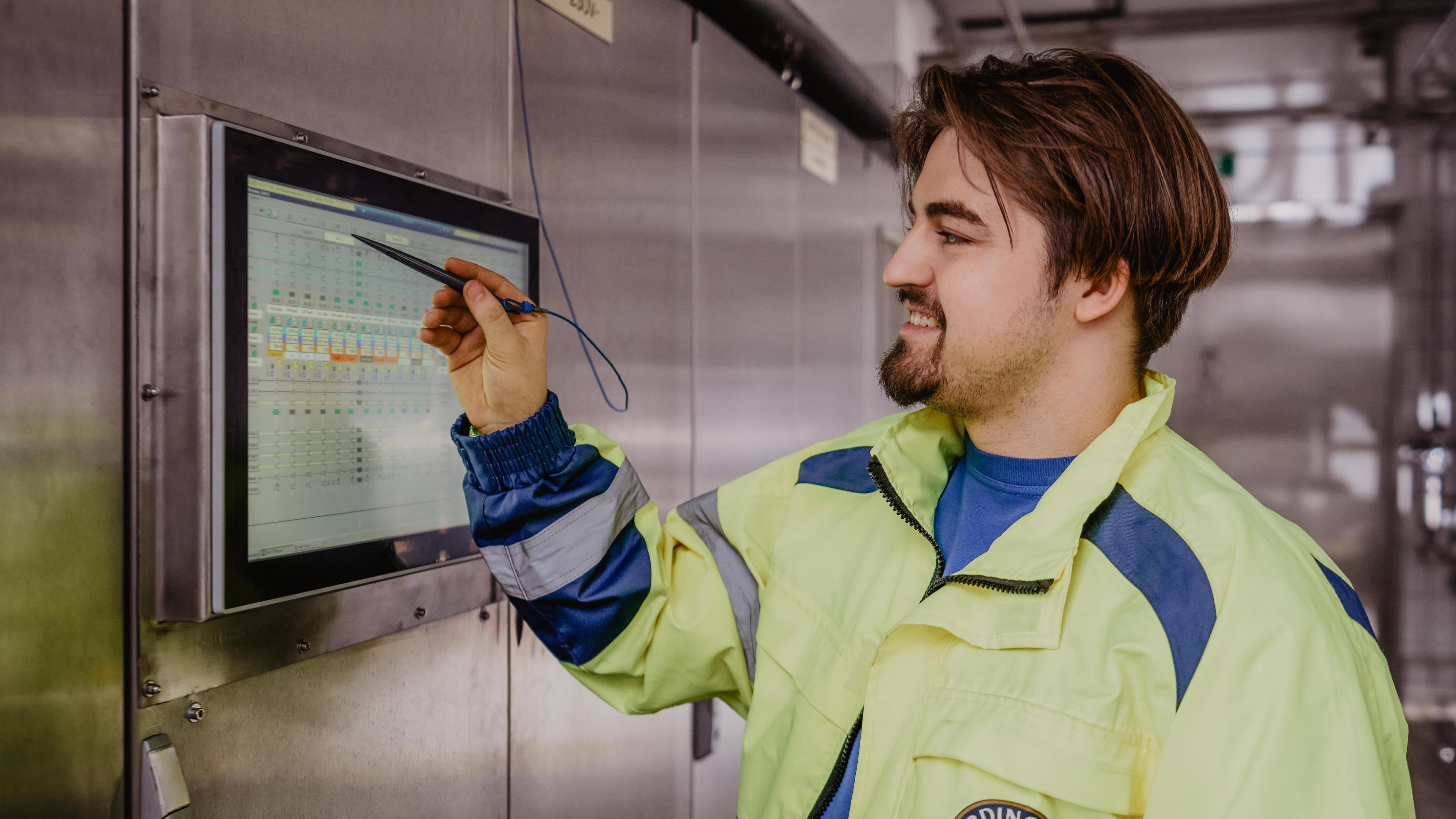 Ein ERDINGER Mitarbeiter bedient einen Touchscreen an der Wand in der Brauerei.