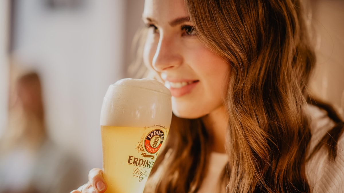 Eine Frau riecht an einem ERDINGER Weißbier im Glas.
