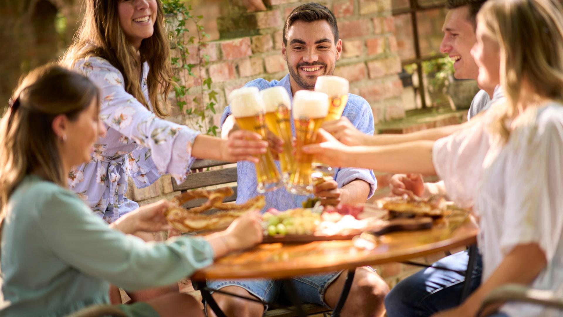 Eine gesellige Runde stößt mit ERDINGER Weißbier an.