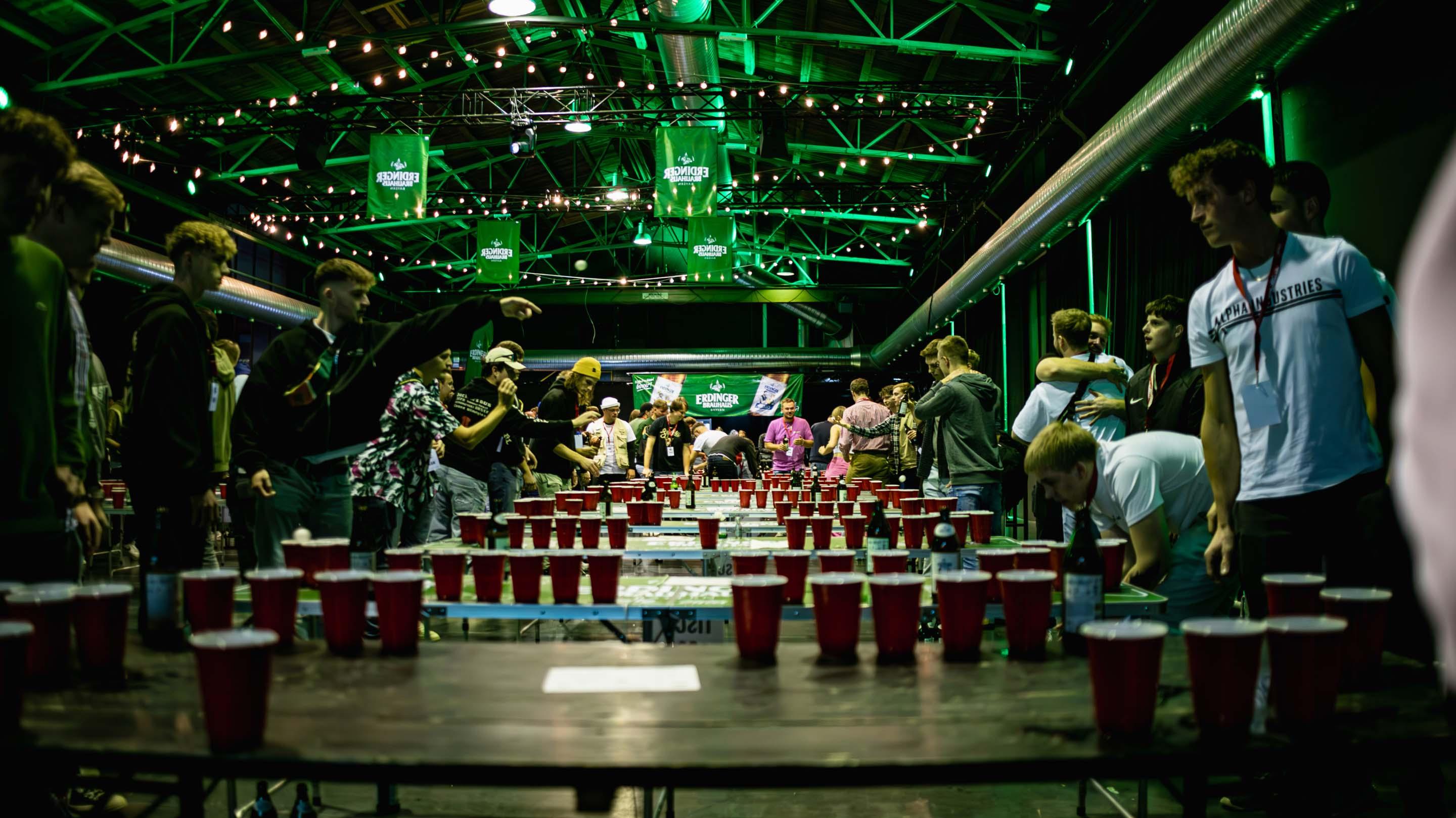 Viele Menschen spielen Beerpong an mehereren Tischen in einer Halle im ERDINGER Brauhaus Branding