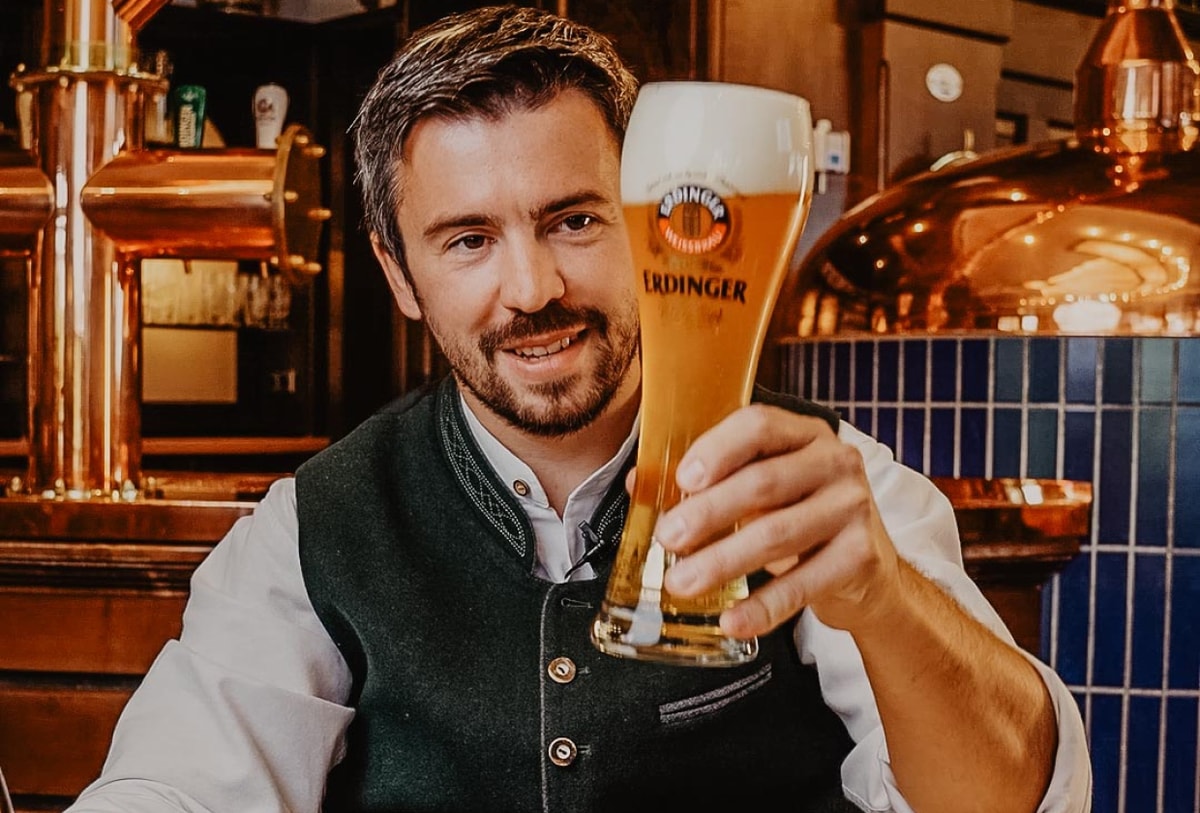 Ein Barkeeper lächelt und macht mit beiden Händen die Daumen-Hoch-Geste.