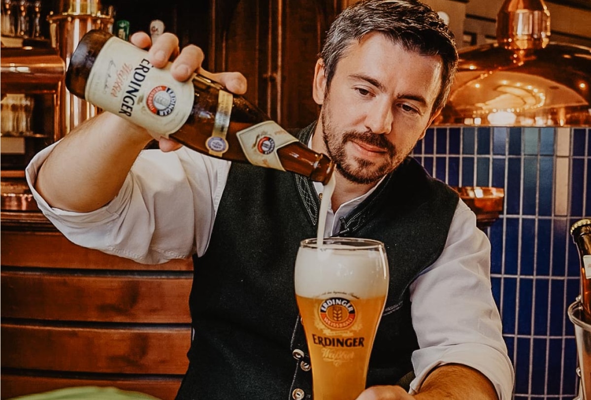 Ein Barkeeper betrachtet die Schaumkrone vom ERDINGER Weißbier.