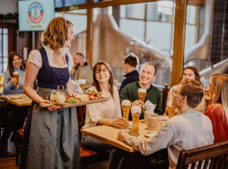 Bedienung bringt geselliger Runde Brotzeit im ERDINGER Besucherzentrum.