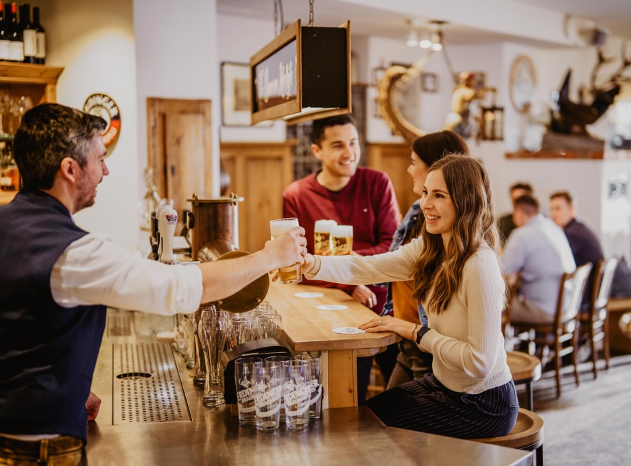 ERDINGER Mitarbeiter gibt Kollegin ein Bier am Schanktresen.