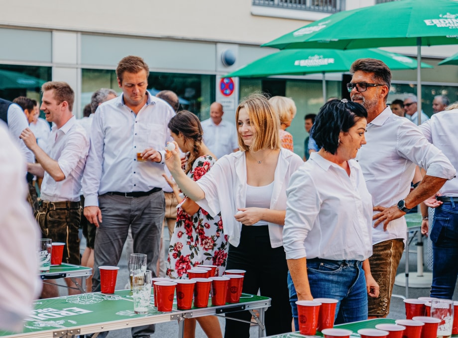 Kollegen spielen zusammen Beerpong bei ERDINGER Bierpongturnier.