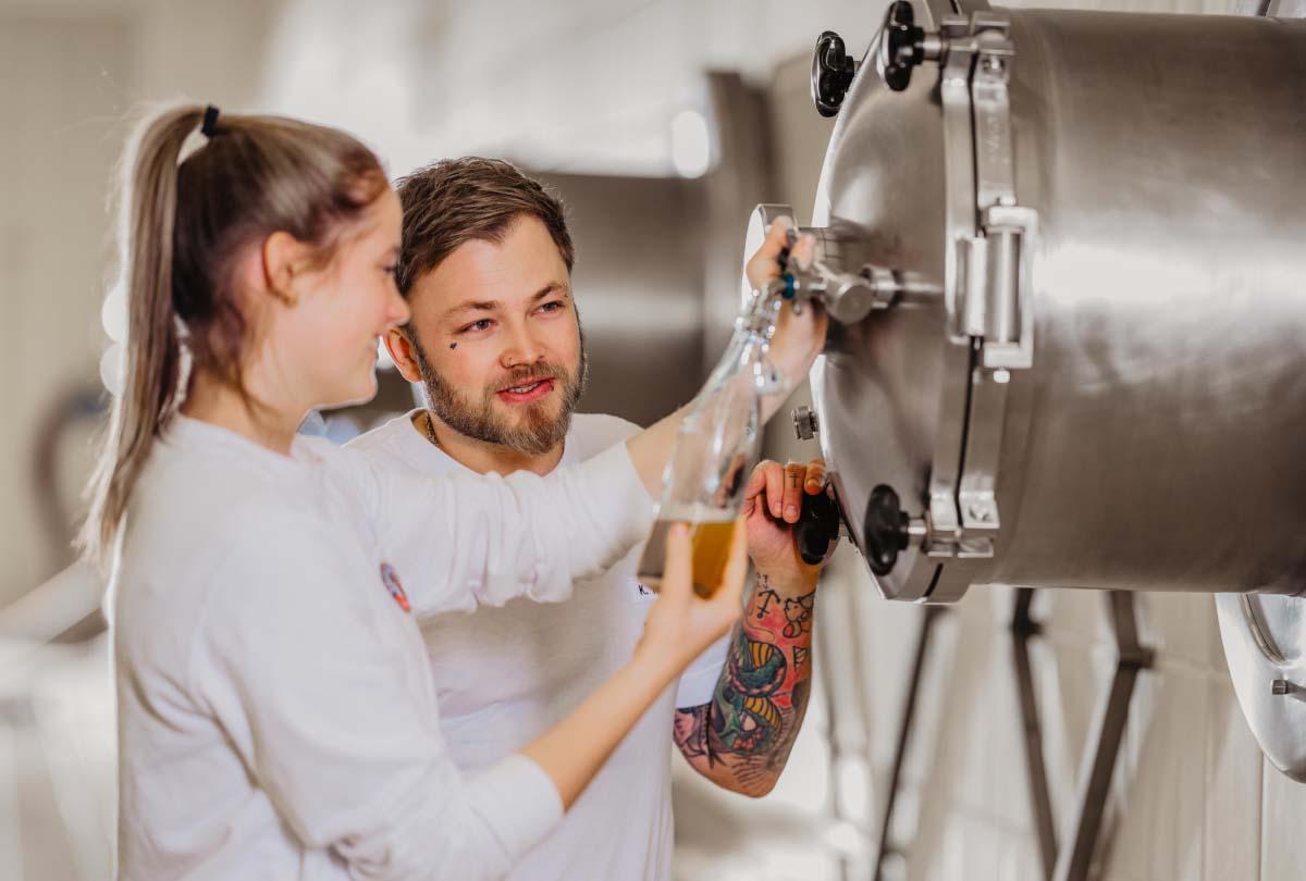 Zwei ERDINGER Brauer nehmen Bierprobe im Gärkeller.