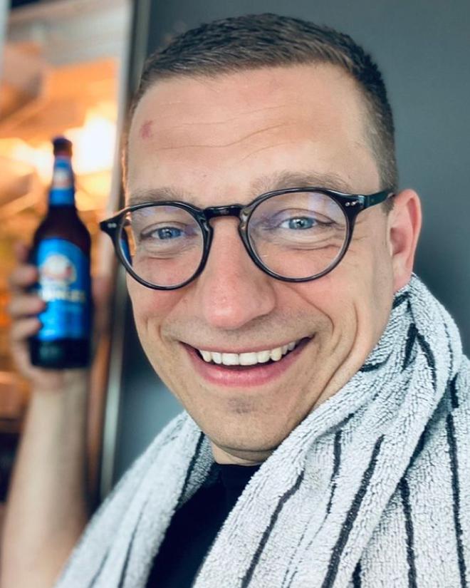 Ein Mann mit Handtuch über der Schulter lächelt mit einem ERDINGER Alkoholfrei in der Hand.