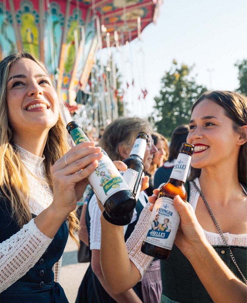 Frauen prosten sich auf einem Volksfest zu mit ERDINGER Brauhaus Hellem.